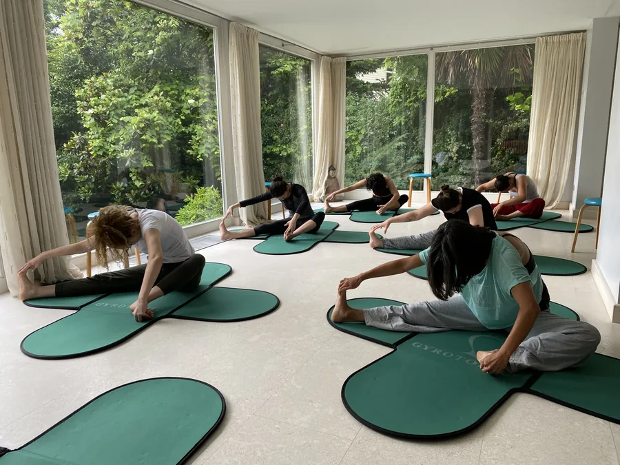 Sandalyede oturarak öne uzanan Gyrokinesis® katılımcıları
