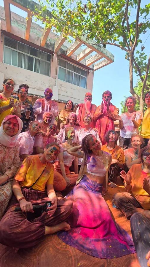 Holi kutlamasında renklere bulanmış, yere oturmuş kamp grubu
