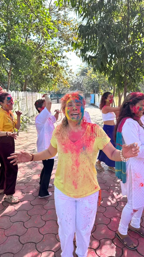 Holi kutlamasında renklere bulanmış, kollarını açan katılımcı