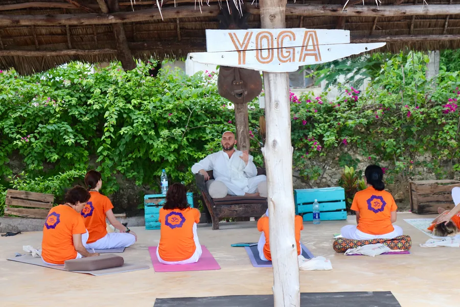 Yoga tabelalı açık hava salonunda eğitmenle çalışan katılımcılar